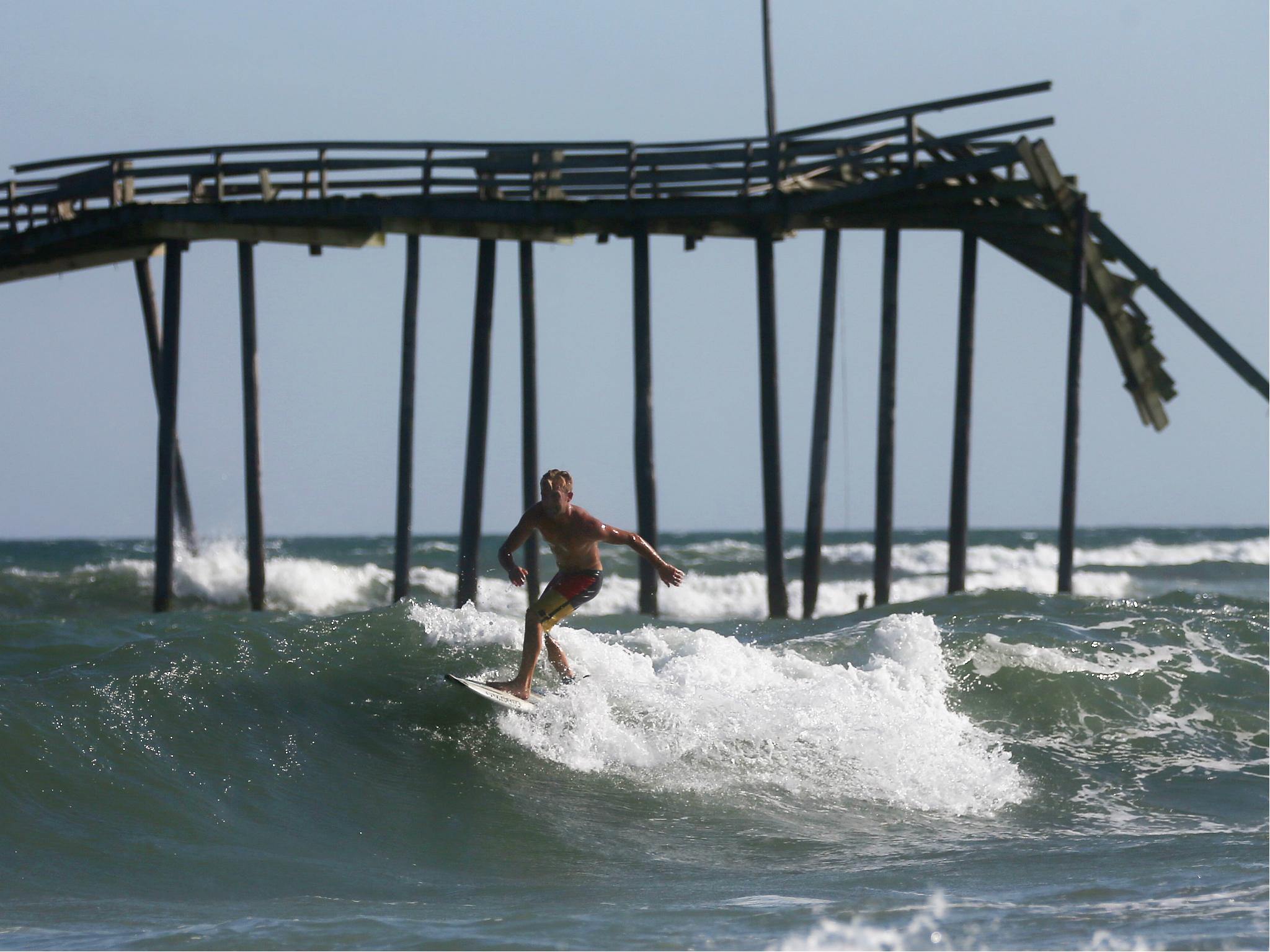 A man surfs near Cape Hatteras in Outer Banks, North Carolina where a new island has formed and storms are common