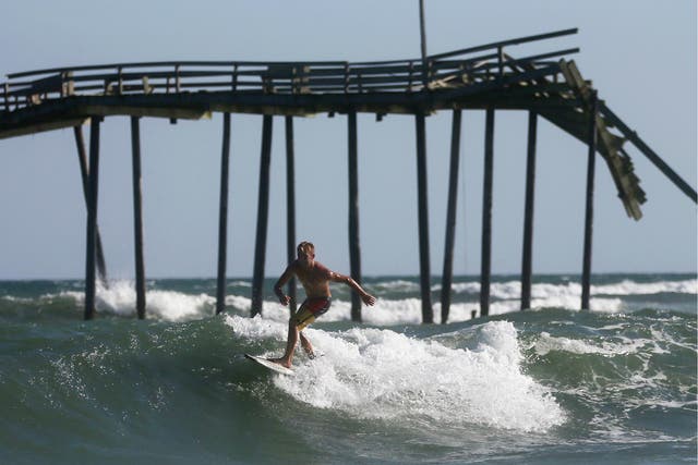 A man surfs near Cape Hatteras in Outer Banks, North Carolina where a new island has formed and storms are common
