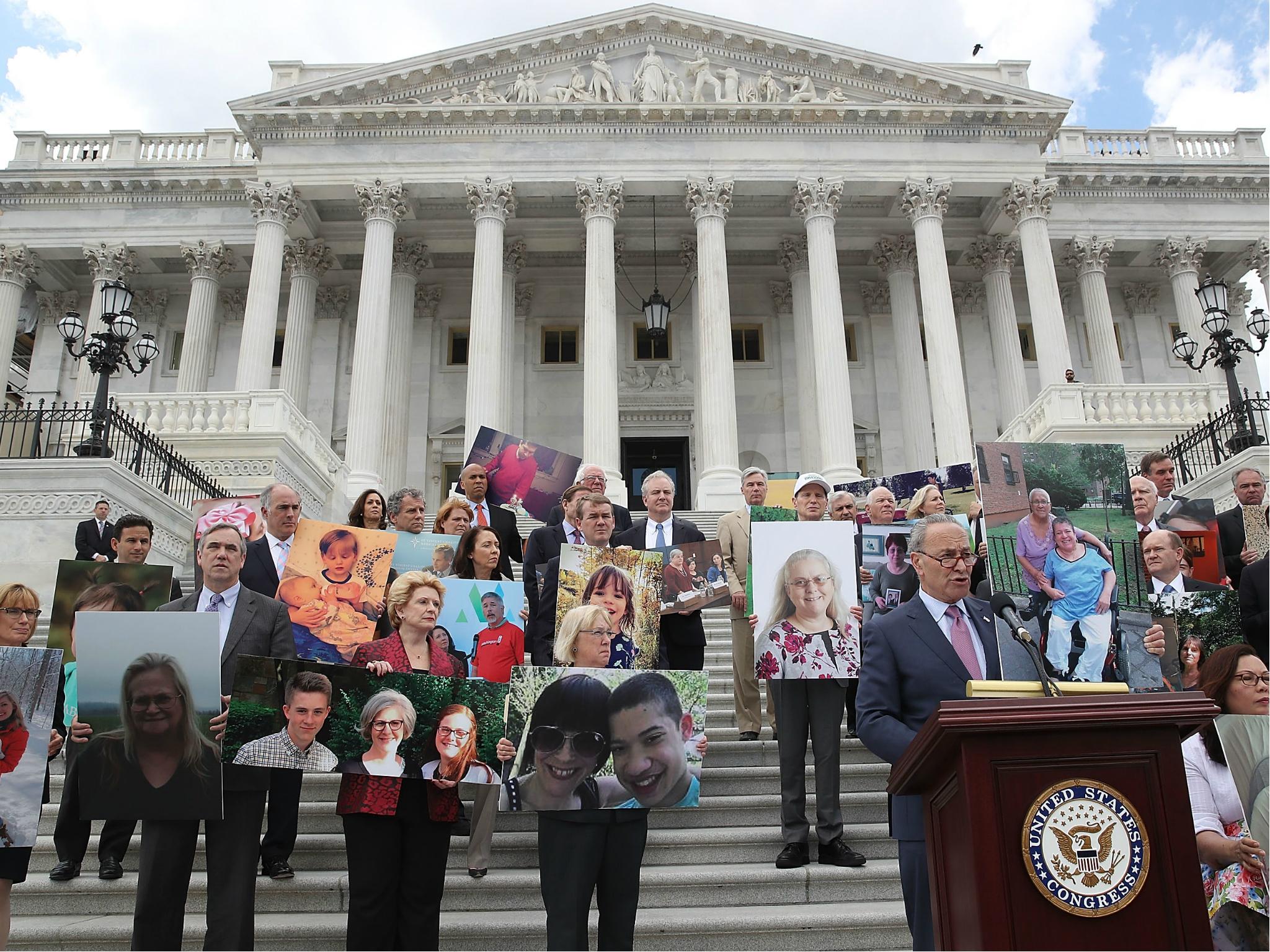 Senate Minority Leader Chuck Schumer speaks while flanked by Senate Democrats holding photos of people who would lose their health coverage under the Senate Republicans healthcare bill during a press conference at the US Capitol on 27 June 2017