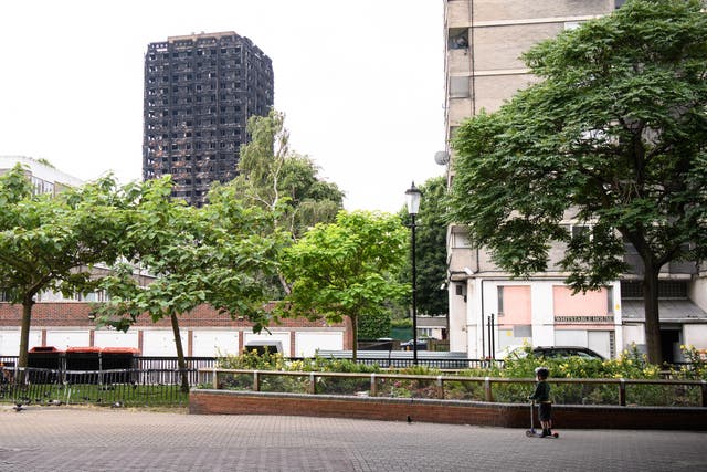 A boy looks upwards at the remains of Grenfell Tower