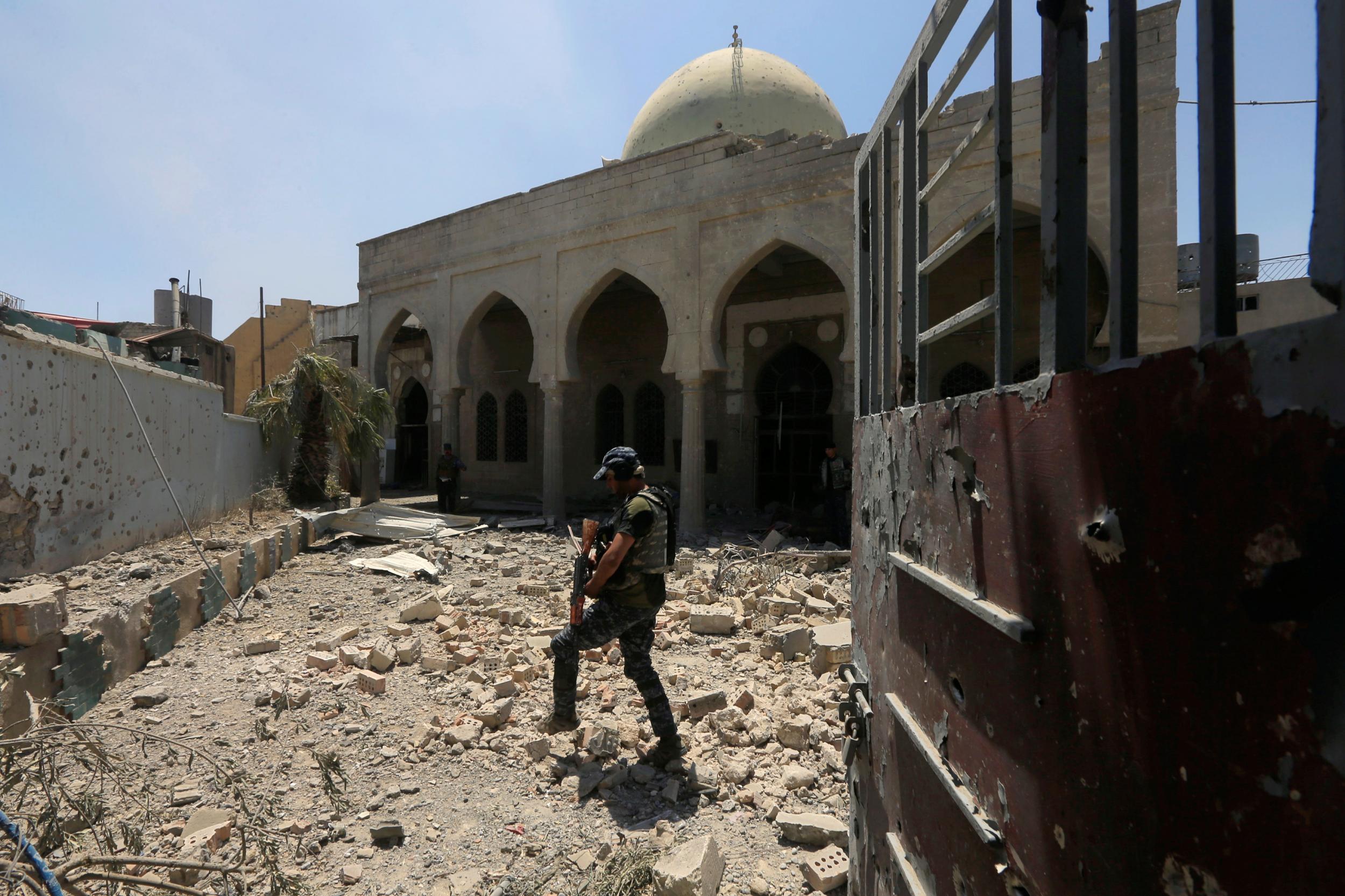A member of Iraqi Federal Police walks through the rubble outside a mosque in Mosul's Old City