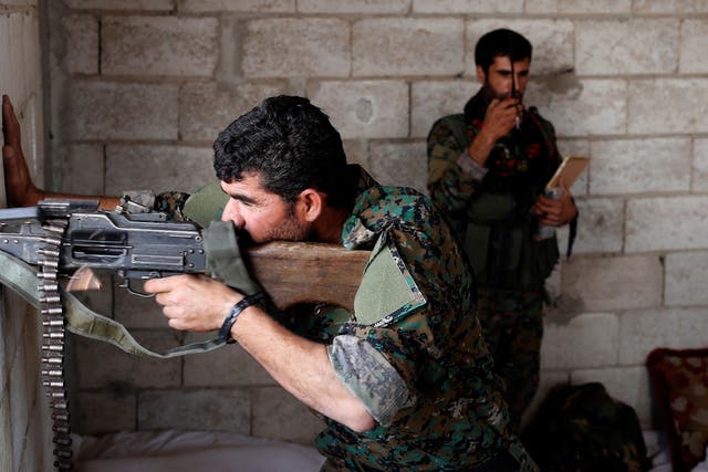 A Kurdish fighter from the People's Protection Units (YPG) fires his weapon from a house in Raqqa