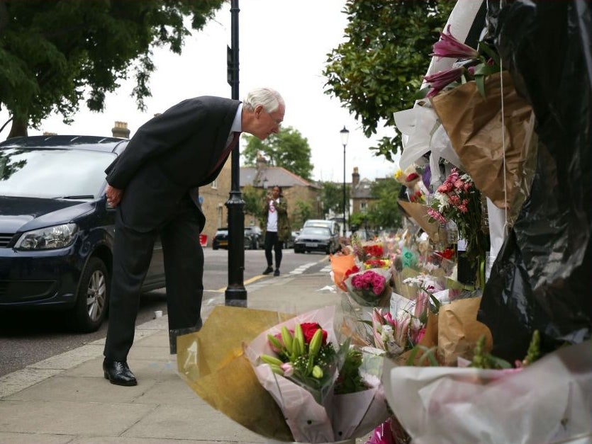 Sir Martin Moore-Bick reading floral tributes to the victims outside Grenfell Tower after meeting with residents