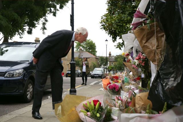 Sir Martin Moore-Bick reading floral tributes to the victims outside Grenfell Tower after meeting with residents