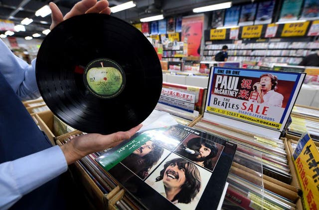 A shop manager shows off a Japanese pressing of The Beatles' final studio album Let It Be at a music shop in Tokyo's Shibuya district, Japan.