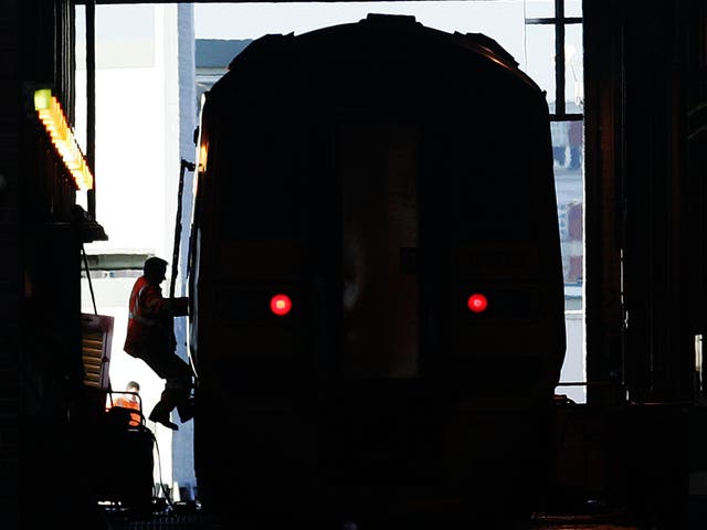 A worker scales a train at a rail depot