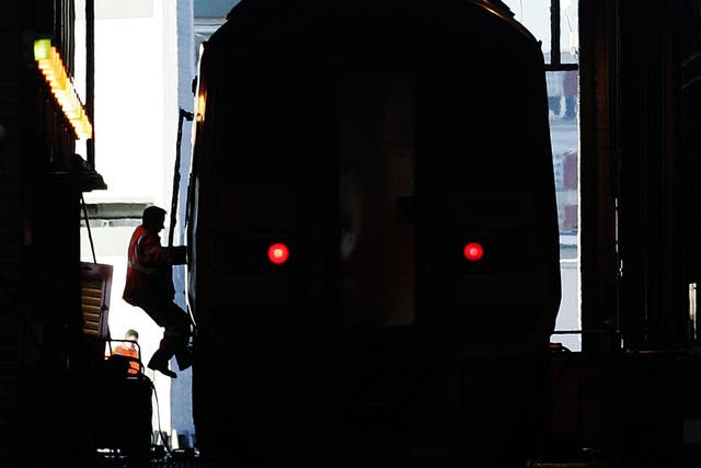 A worker scales a train at a rail depot
