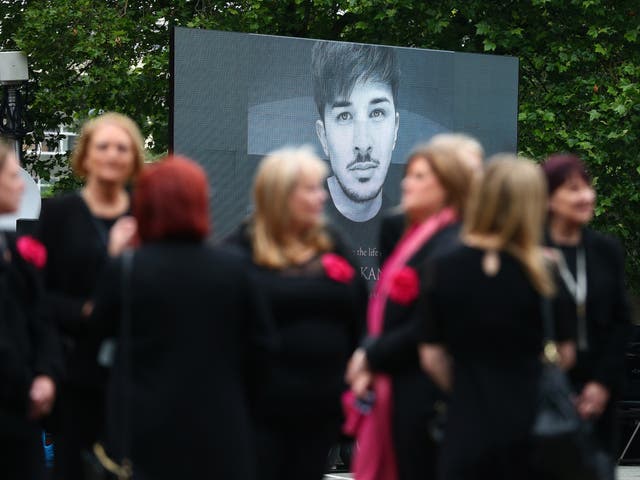 A screen displaying an image of Martyn Hett as mourners arrive for his funeral in Stockport, 2017