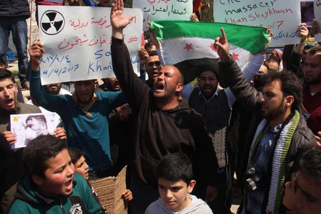 Syrian residents of Khan Sheikhun hold placards and pictures on 7 April during a protest condemning a suspected chemical weapons attack on their town that killed at least 86 people