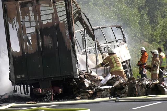 Firefighters at the scene after a coach burst into flames after colliding with a lorry on a motorway near Muenchberg, Germany