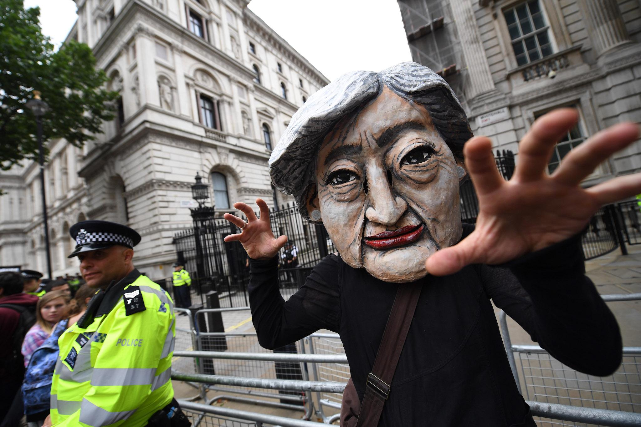A protester wears a Theresa May mask during the 'Not One Day More' march outside of Downing Street on July 1, 2017 in London, England
