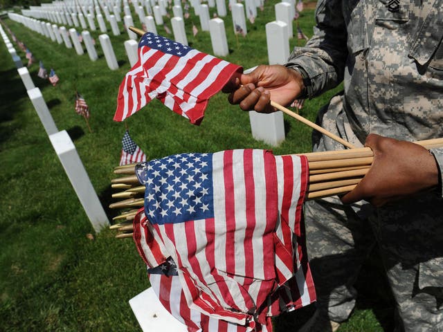 Sergeant 1st Class James Gordon III of the 3rd US Infantry Regiment prepares to place a flag at Arlington National Cemetery before Memorial Day