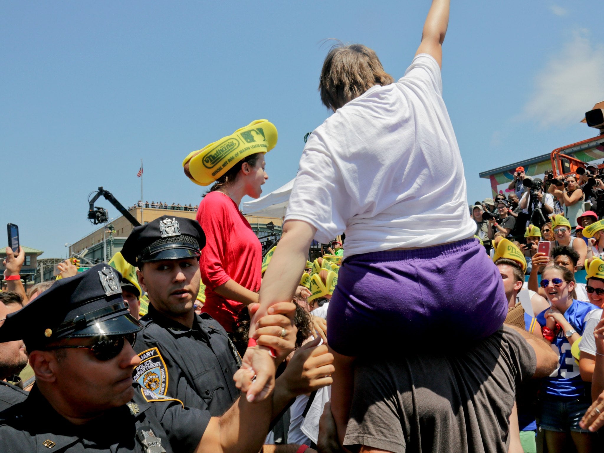 Police remove activists as they try to protest the hot dog eating contest