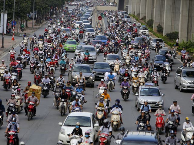 <p>Motorbikes and cars fight for space on a street in Hanoi, Vietnam</p>