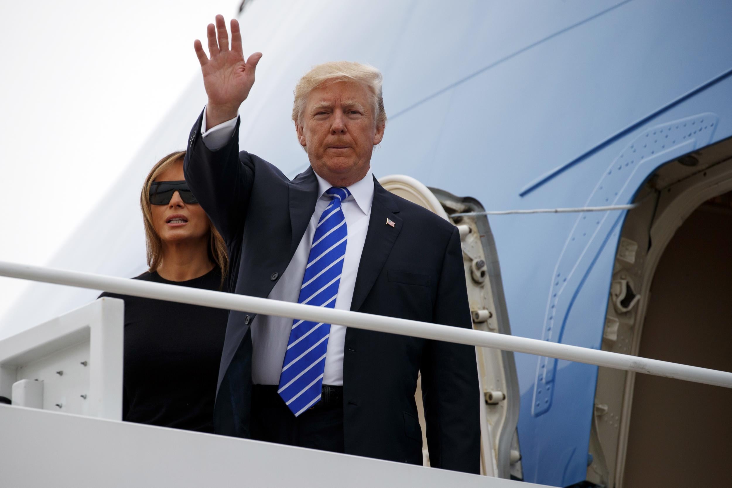 President Donald Trump waves as he boards Air Force One with first lady Melania Trump for a trip to Poland