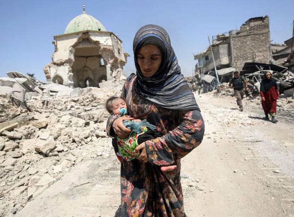 A woman, carrying her baby, flees the Old City of Mosul as Iraqi government forces close in