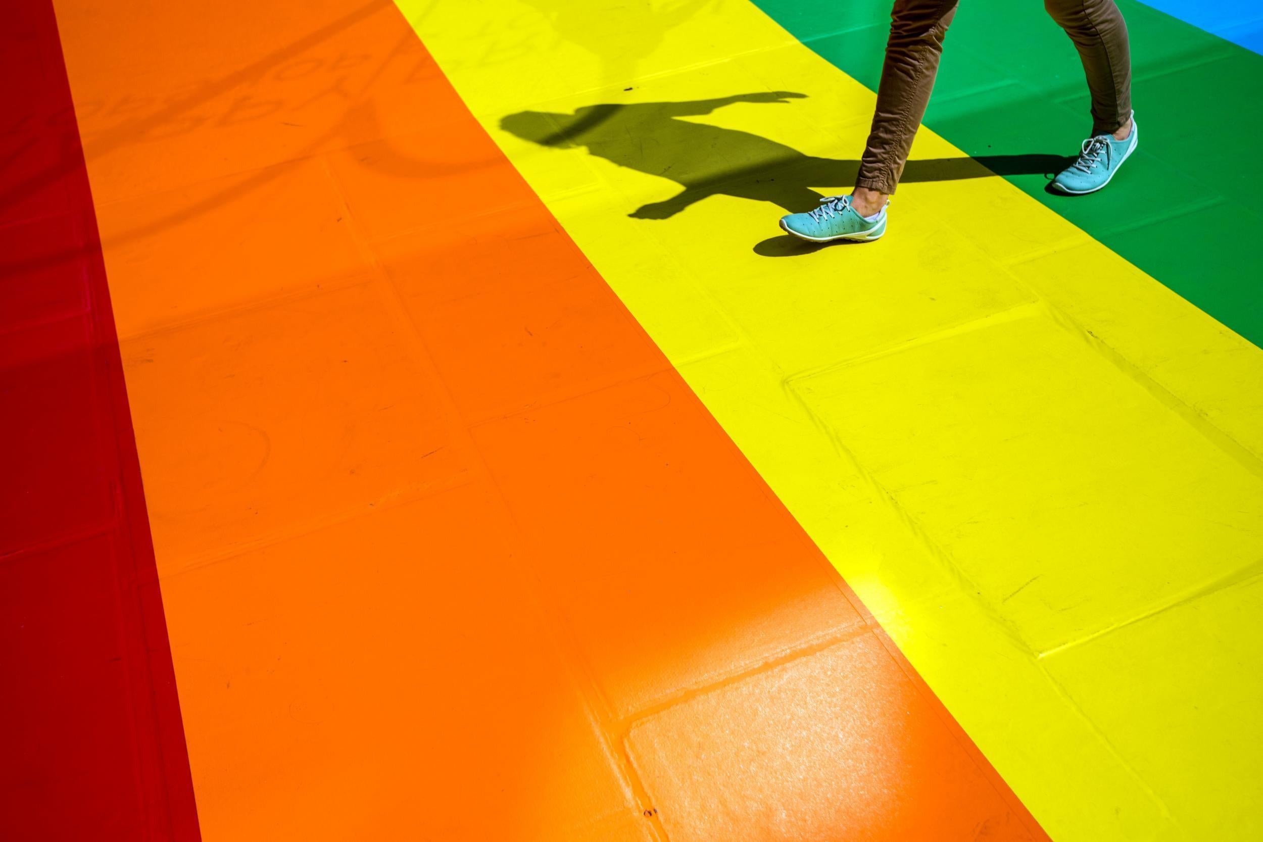 A woman walks past a shop front decorated with the Pride flag colours
