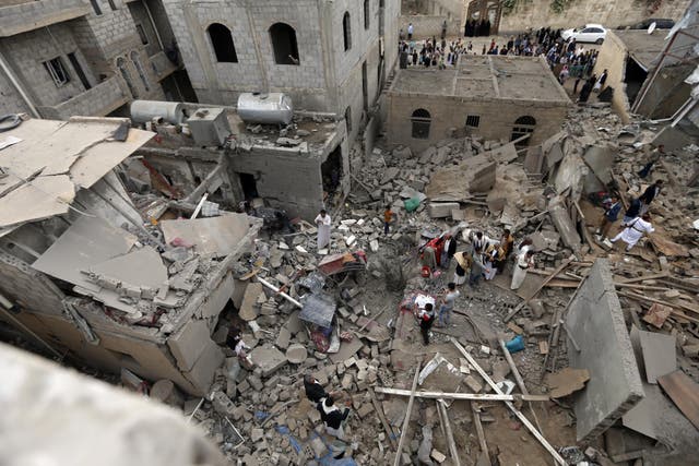 Yemenis stand on the rubble of houses destroyed by an air strike 