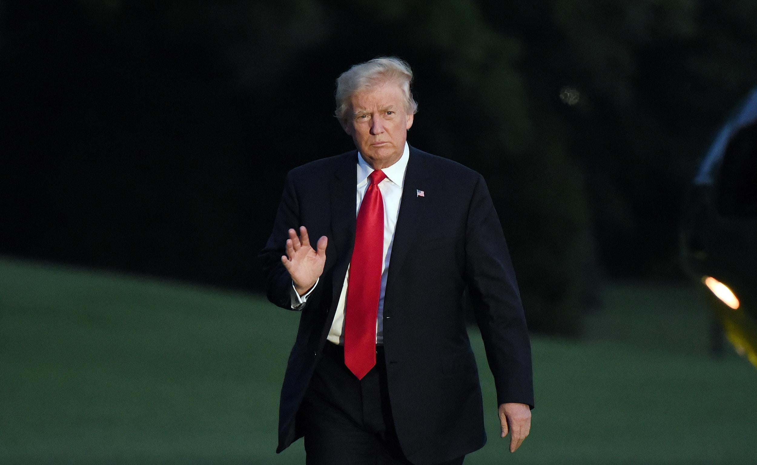 President Donald Trump waves as he returns to the White House