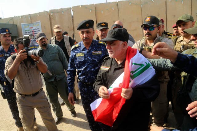 Prime Minister Haider al-Abadi, holding the Iraqi national flag, arrives in Mosul on Sunday
