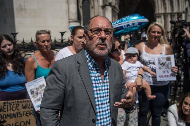 Supporters of Chris Gard and Connie Yates, the parents of terminally ill toddler Charlie Gard, look on as Reverend Patrick Mahoney speaks to the media outside the High Court
