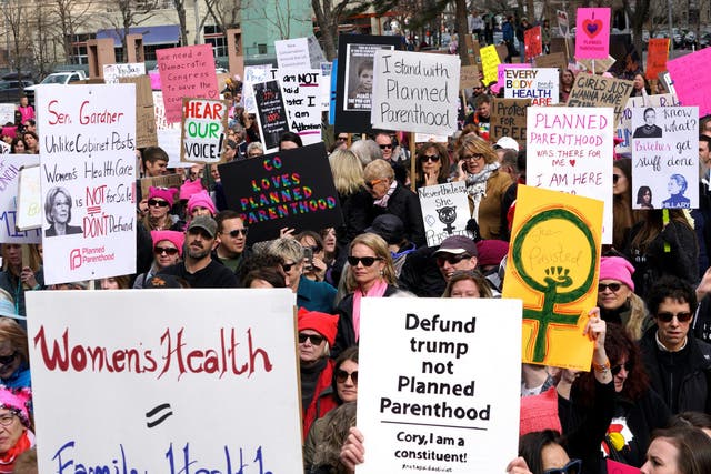 Planned Parenthood supporters hold signs at a protest in downtown Denver