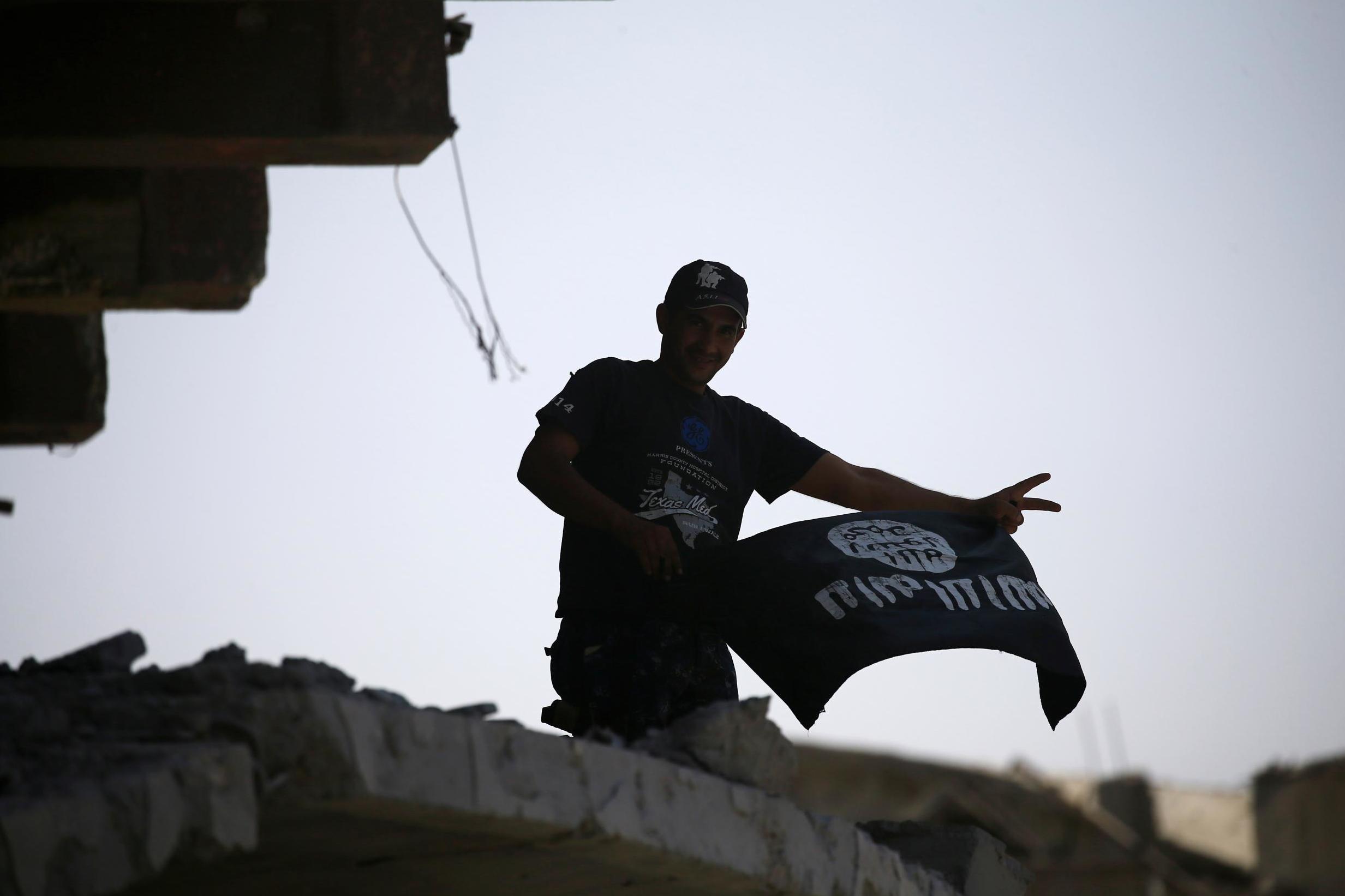 A member of the Iraqi security forces celebrates as he holds the Isis flag on the top of a destroyed building from clashes in the Old City of Mosul on 10 July 2017.