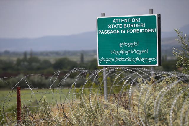 A warning sign is pictured behind a wire barricade erected by Russian and Ossetian troops along Georgia's de-facto border with its breakaway region of South Ossetia in 2015