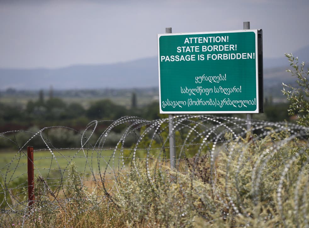 A warning sign is pictured behind a wire barricade erected by Russian and Ossetian troops along Georgia's de-facto border with its breakaway region of South Ossetia in 2015