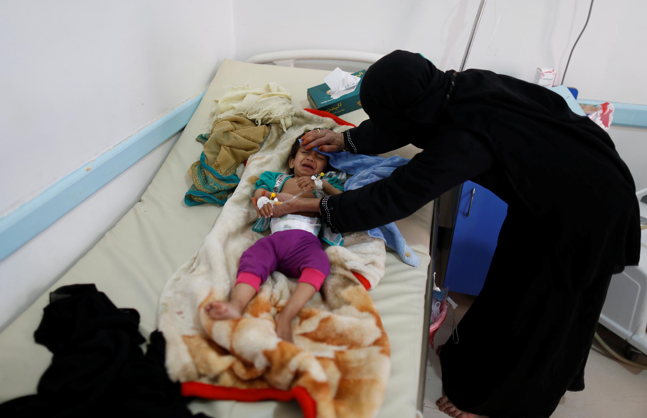 A woman helps her son as he lies on a bed at a cholera treatment centre in Sanaa, Yemen on 6 June 2017