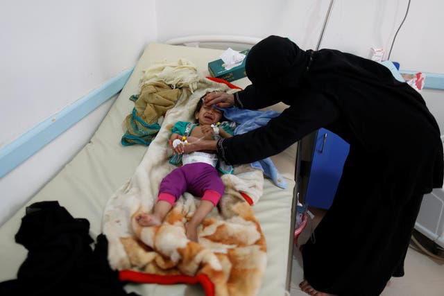 A woman helps her son as he lies on a bed at a cholera treatment centre in Sanaa, Yemen on 6 June 2017