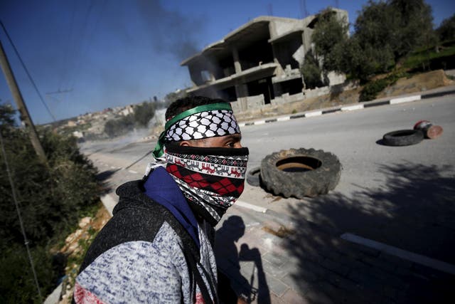 A Palestinian protester takes cover during clashes with Israeli troops in the West Bank village of Araka near Jenin in this file photo from 15 February 2016