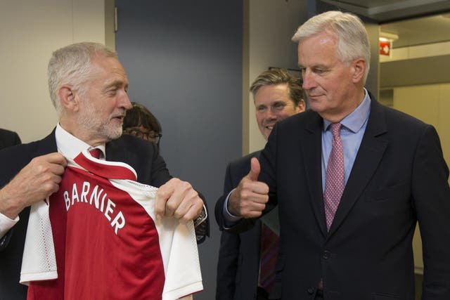 The EU chief Brexit negotiator Michel Barnier, right, receives an Arsenal football top from Labour Party leader Jeremy Corbyn prior to a meeting at EU headquarters in Brussels