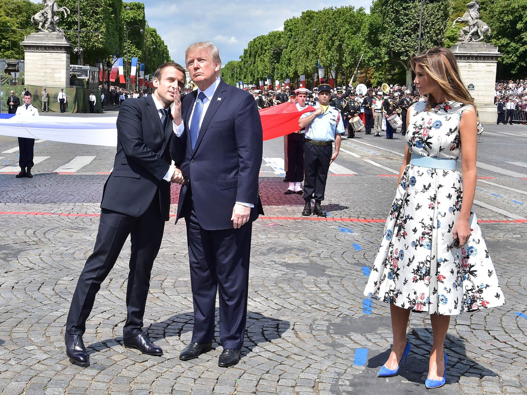 Emmanuel Macron, the French President, shakes hands with Donald Trump, the President of the United States, next to Melania Trump, the First Lady of the US, during the annual Bastille Day military parade on the Champs-Elysees