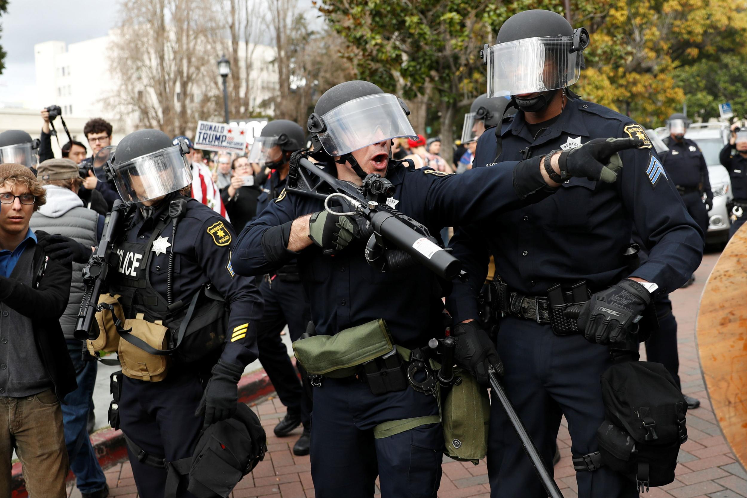 A police officer gestures as supporters of Donald Trump and counter-protesters scuffle at Berkeley earlier this year