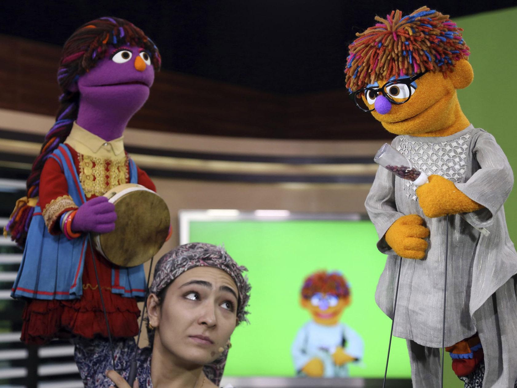 An Afghan puppeteer with the two new Sesame Garden characters: Zari, left, and Zeerak