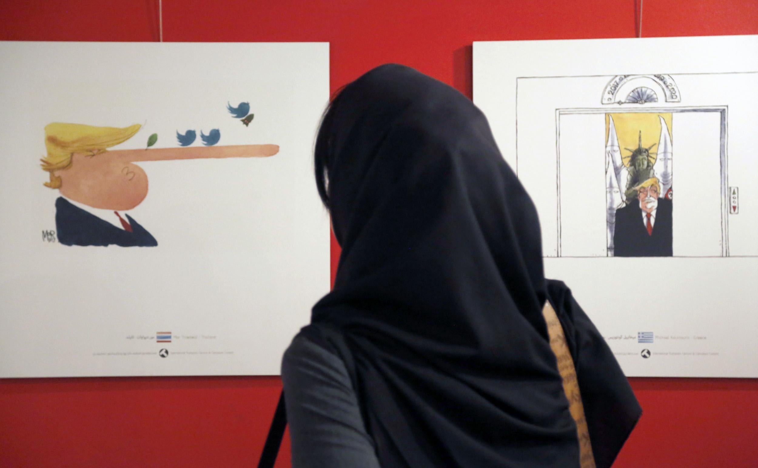 An Iranian woman looks at cartoons of US President Donald Trump at an exhibition of the Islamic Republic's new International Trumpism cartoon and caricature contest in Tehran on 3 July 3 3017