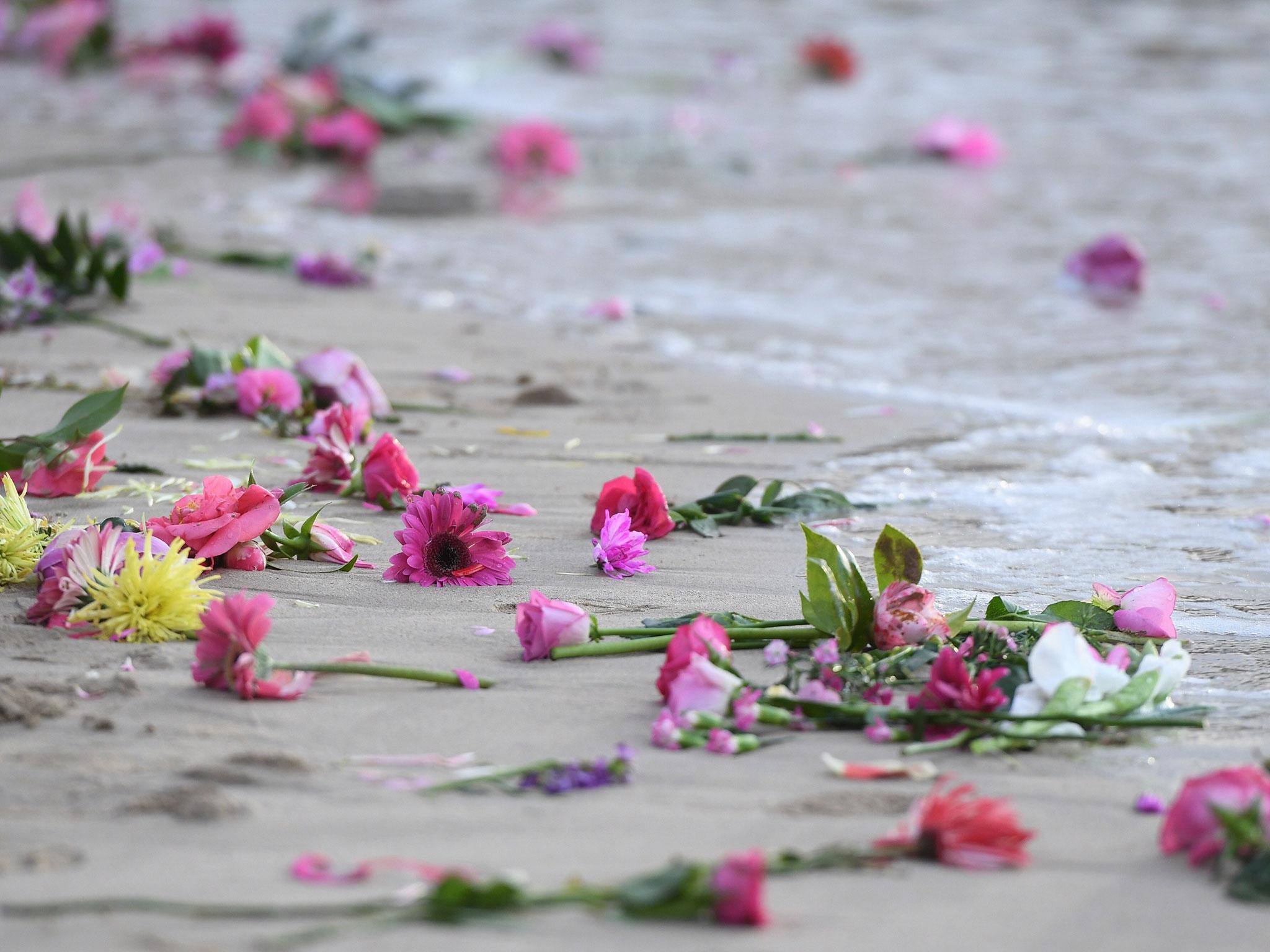 Hundreds of pink flowers wash onto the beach after family and friends gathered on Freshwater Beach for a candlelight vigil, where they threw hundreds of pink flowers into the ocean for Justine Damond