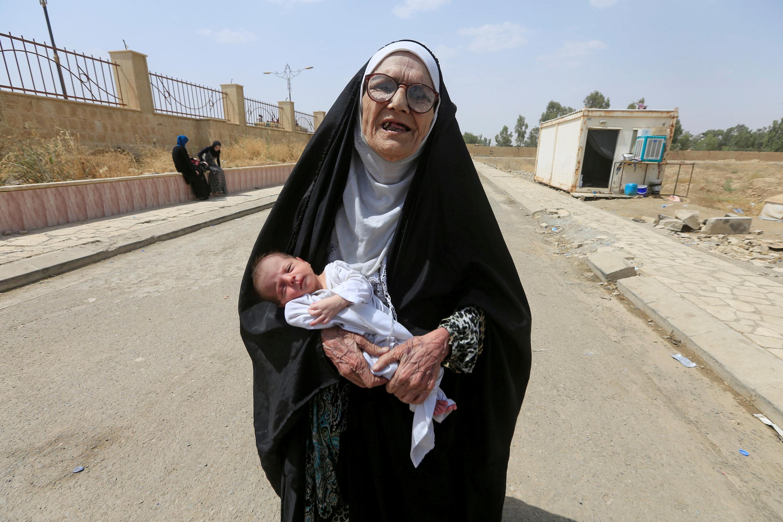 An elderly displaced Iraqi woman who fled from Isis militants carries a baby in Mosul