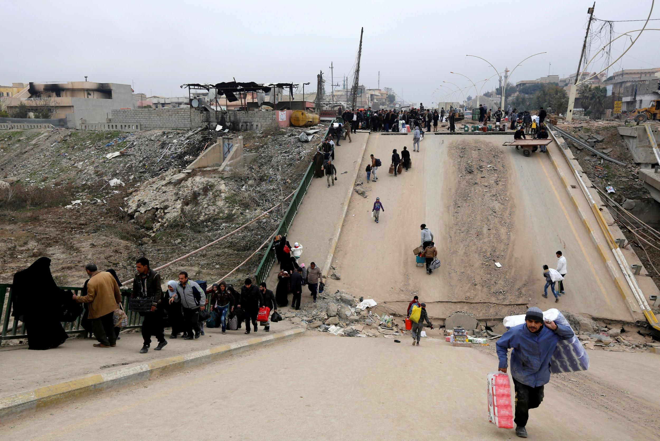 Displaced people, who fled Isis, cross the bridge in Al-Muthanna neighbourhood of Mosul