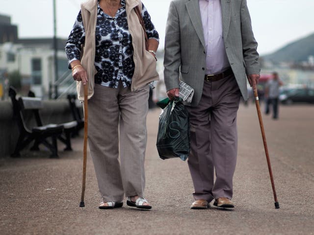 A retired man and woman walk along Llandudno Promenade in Wales