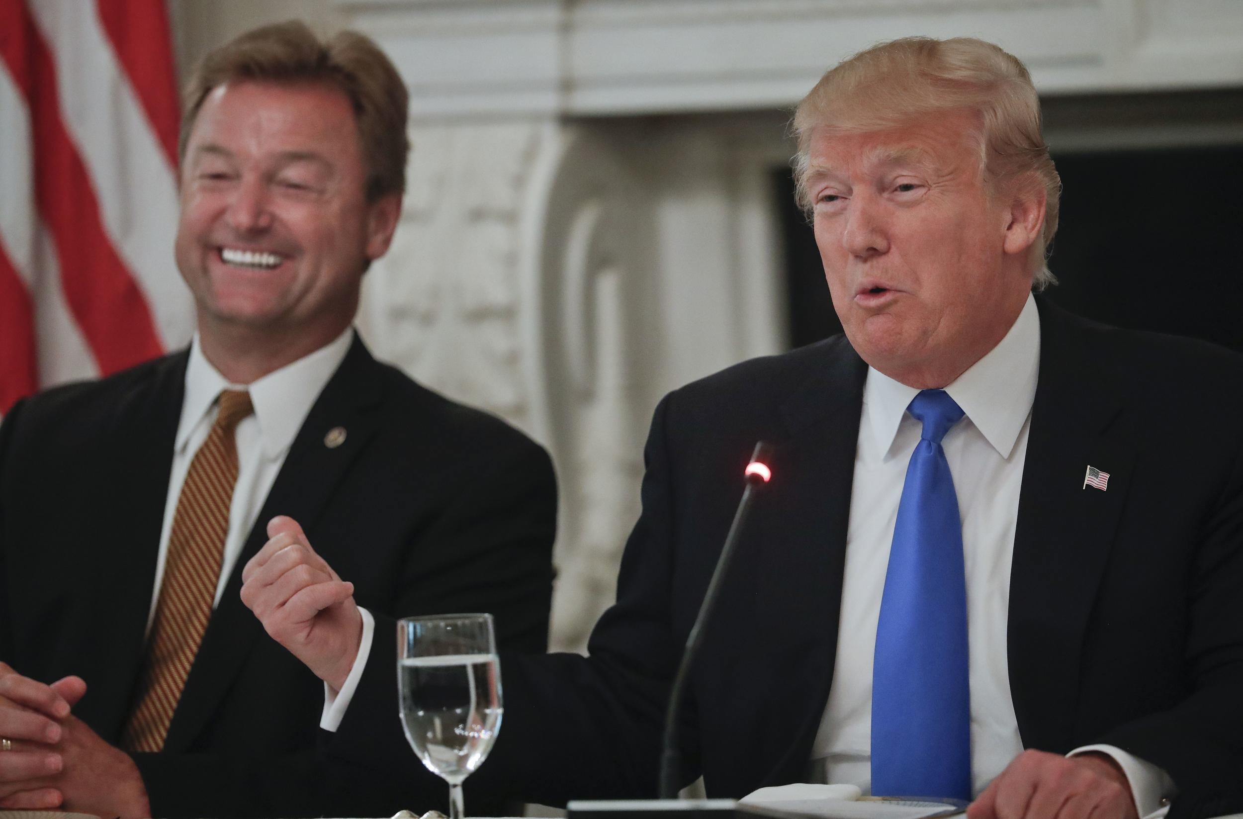 President Donald Trump gestures towards Senator Dean Heller while speaking during a luncheon
