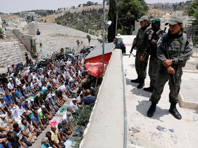 Israeli Border Police stand guard as Palestinian worshipers pray next to the Lions gate of the old city of Jerusalem