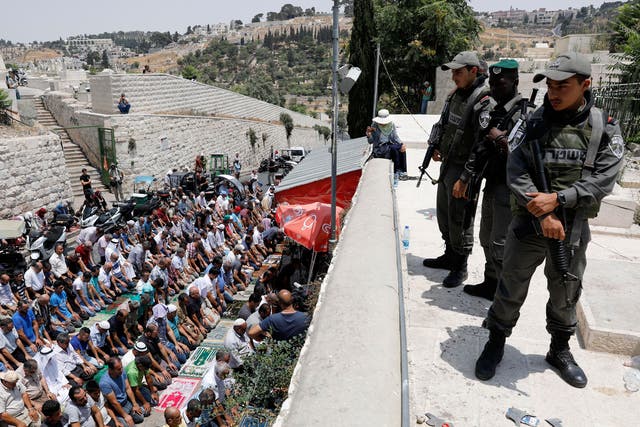 Israeli Border Police stand guard as Palestinian worshipers pray next to the Lions gate of the old city of Jerusalem