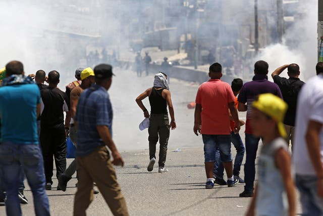 Israeli soldiers fire tear gas at Palestinian protesters during clashes after a protest at Qalandiya checkpoint near the West Bank city of Ramallah on 21 July