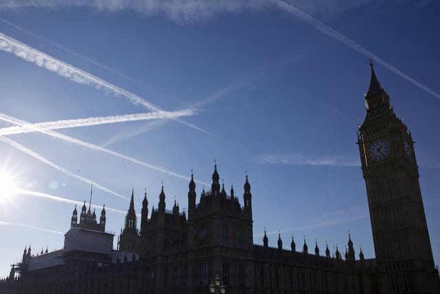 Contrails or vapour trails made by passing aircraft in the sky above the Houses of Parliament