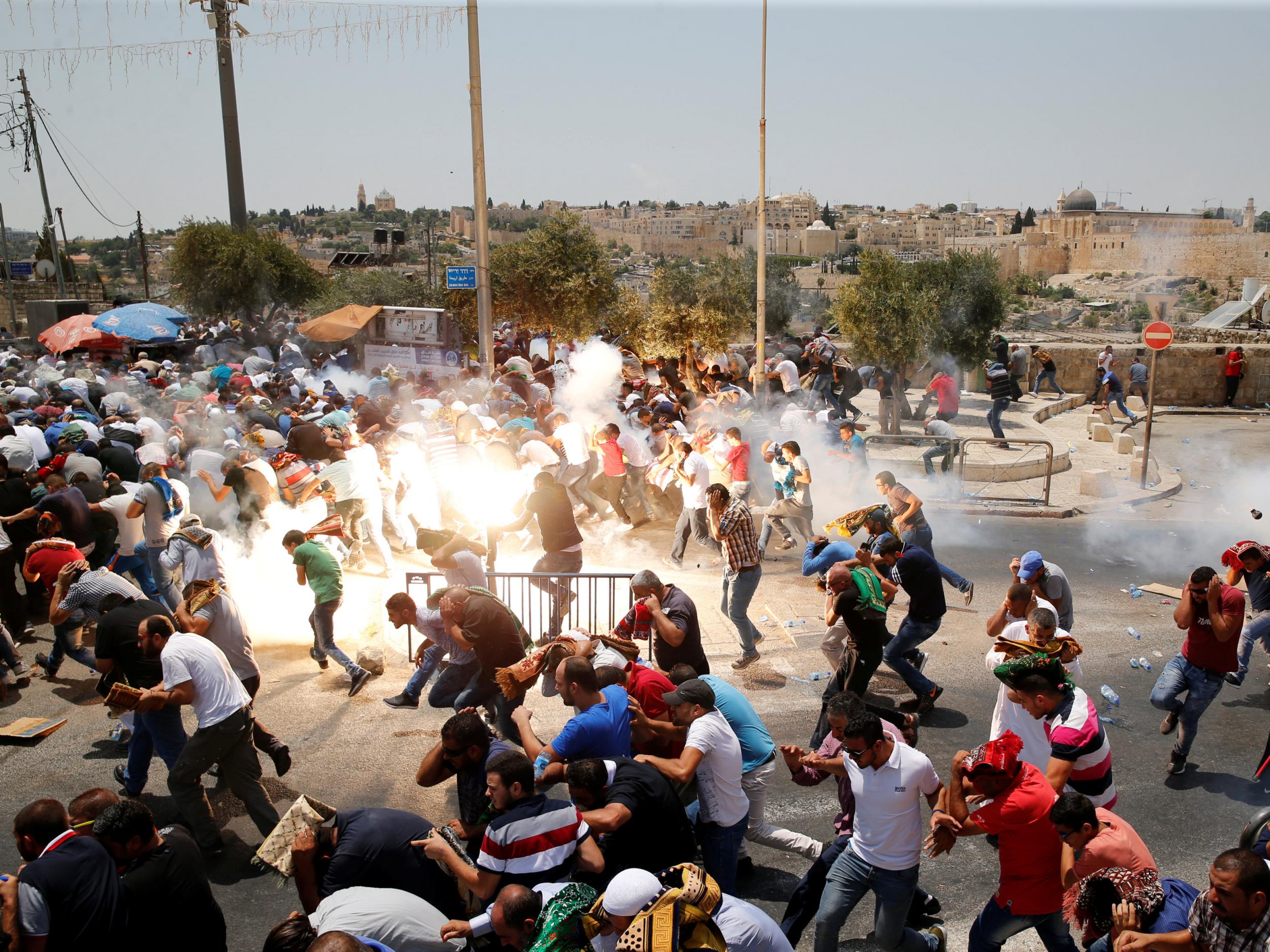 Palestinians react following tear gas that was shot by Israeli forces after Friday prayer on a street outside Jerusalem's Old City