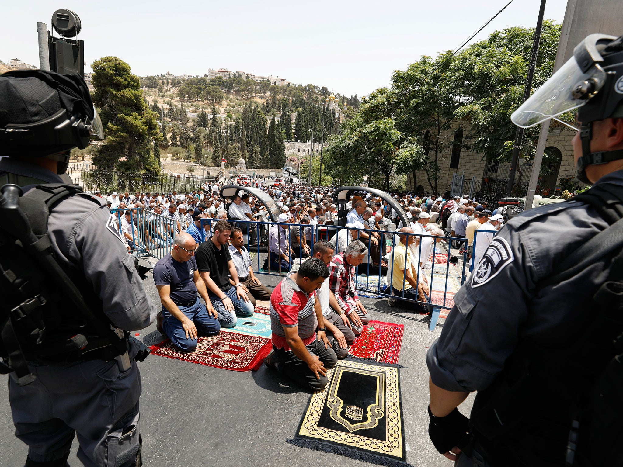 Palestinians pray on the street close to Lion's Gate in the Old City of Jerusalem, closely watched by Israeli security during a mass street Friday prayer on 21 July 2017.