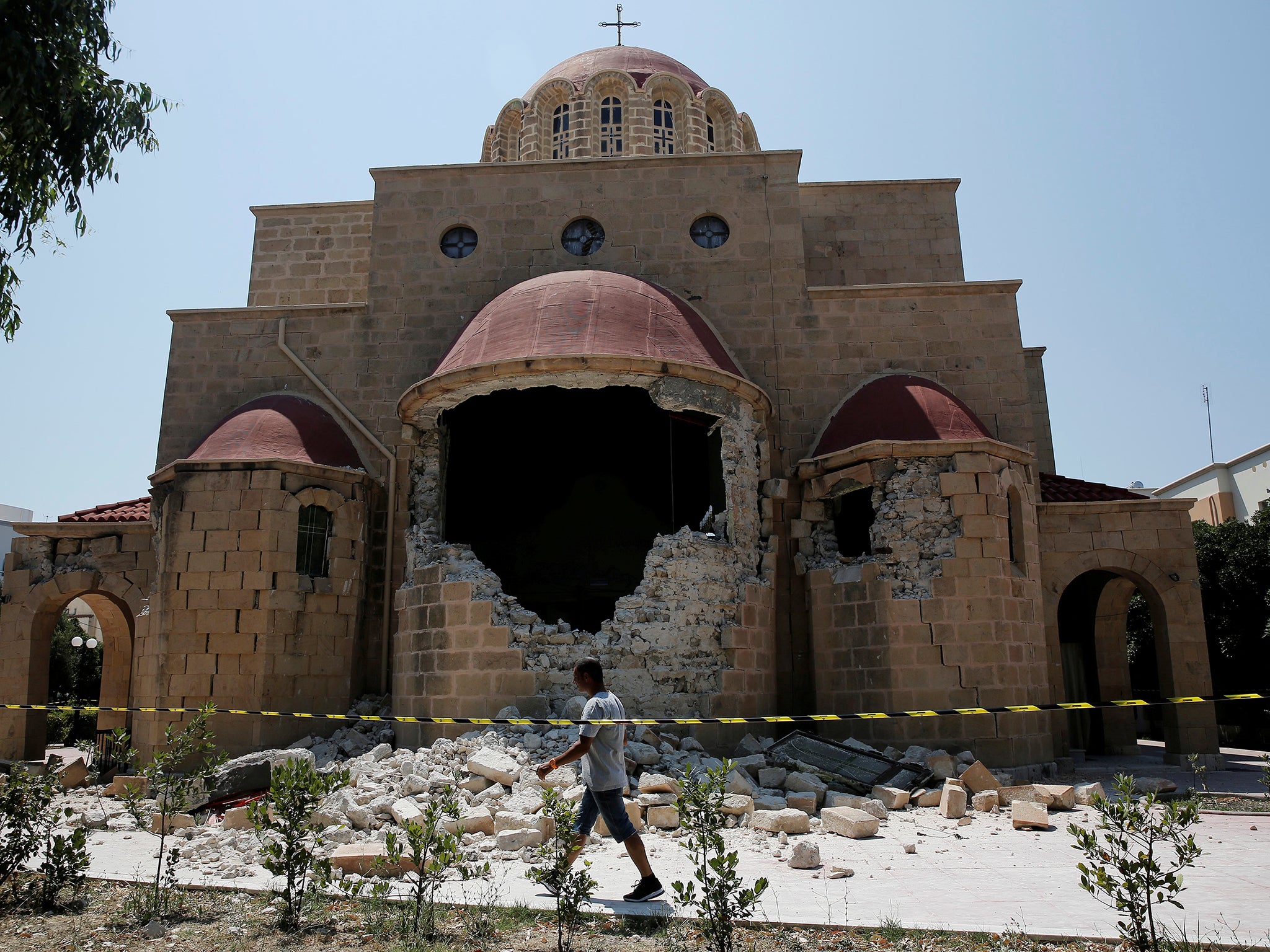 A man walks past a damaged church following an earthquake off the island of Kos