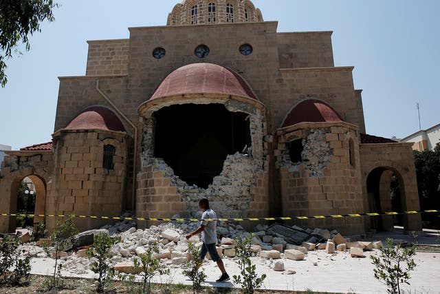 A man walks past a damaged church following an earthquake off the island of Kos